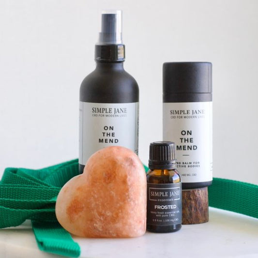 Collection of products to improve flexibility, recovery balm, essential oil, and heart-shaped salt stone on a white background.